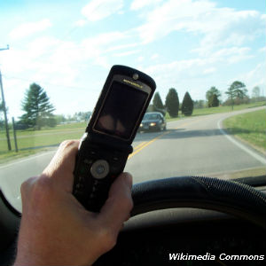 Photo of hand holding cell phone while driving