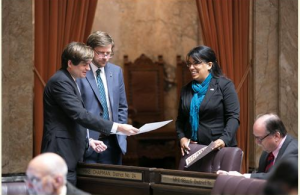 Rep. Mike Chapman (D-Port Angeles) working on the floor of the House of Representatives with Rep. Mike Pellicciotti, left, and Rep. Kristine Reeves, right.