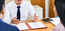 Photo of a man explaining insurance paperwork to couple