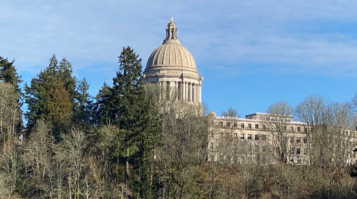 The dome of the Washington state Legislative Building in Olympia peeks above the trees and foliage lining the middle basin of Capitol Lake.