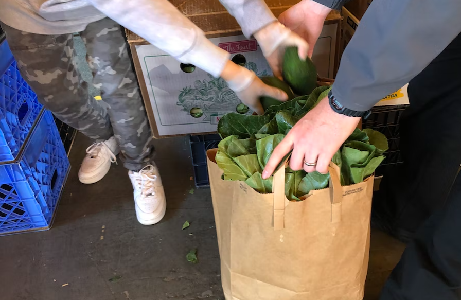 A volunteer at Rainier Valley Food Bank fills a bag with produce. Local food banks are seeing a jump in demand as people struggle to make ends meet.