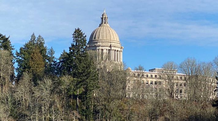 The dome of the Washington state Legislative Building in Olympia peeks above the trees and foliage lining the middle basin of Capitol Lake