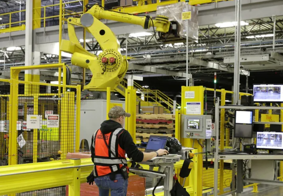 A worker monitors the operation of a large robotic arm above him during a media tour of the Amazon fulfillment center in DuPont in 2015.