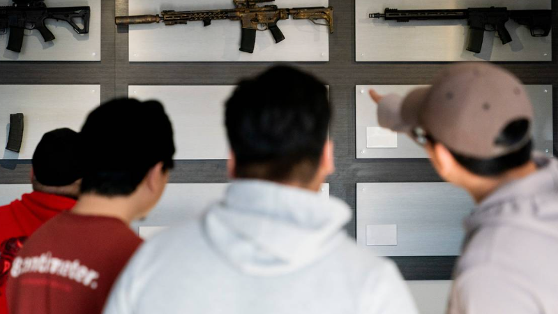 Customers look at AR-15-style rifles on a mostly empty display wall at Rainier Arms Friday, April 14, 2023, in Auburn, Wash.