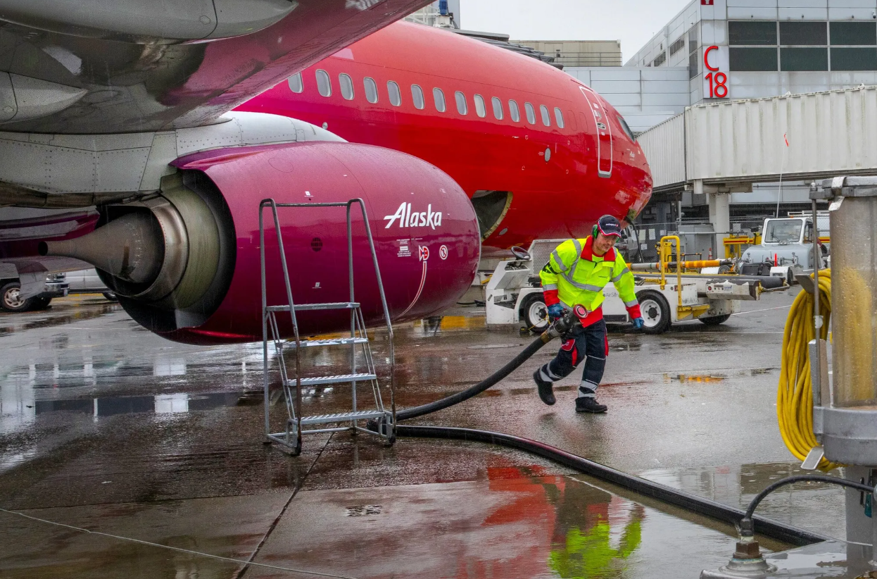 Amer Halilovic, working as a fueling agent, pulls a hose back to a hydrant cart (at right) after refueling an Alaska Airlines jet at Sea-Tac International Airport on Jan. 10, 2020. Dutch company SkyNRG has announced plans to build a massive sustainable aviation fuel refinery in Washington