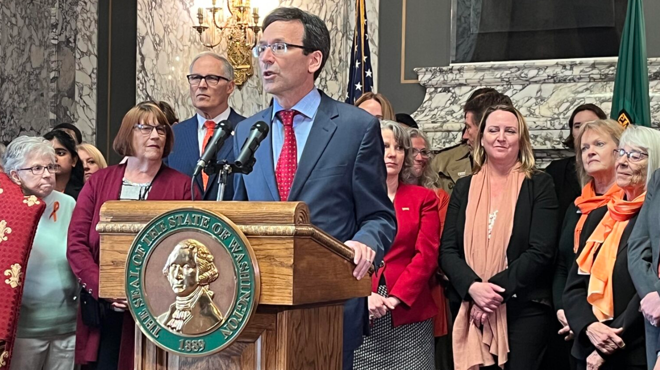 Washington state Attorney General Bob Ferguson (at podium) makes remarks prior to Gov. Jay Inslee (to the left of Ferguson) signing a package of gun legislation in April 2023. The legislation included a ban on the sale of firearms classified as “assault weapons.”