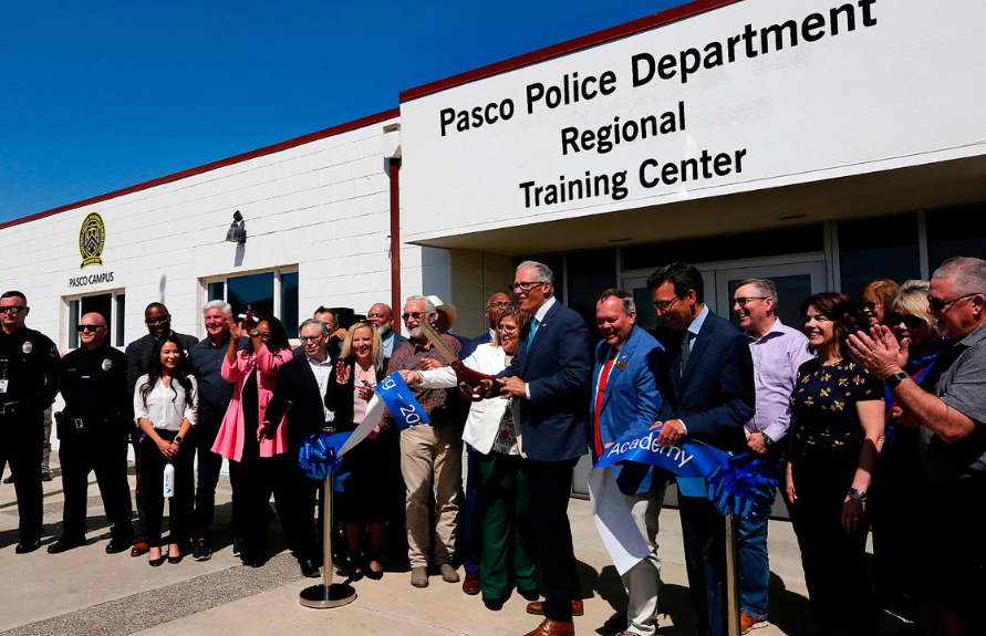 Washington Gov. Jay Inslee is surrounded by community members, law enforcement officials and elected officials for the ribbon cutting ceremony in Pasco.