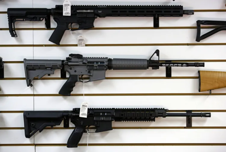 A Ruger AR-15 semi-automatic rifle, center, sits on display with other rifles on a wall in a gun shop in Lynnwood.