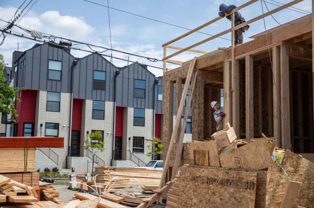 Construction workers complete the framework of a townhome in Ballard on Wednesday, March 24, 2023. In the background are newly built townhomes for sale.