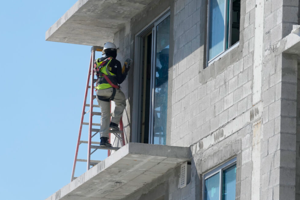 A construction worker sands a door opening at a new apartment complex, Tuesday, February 28, 2023, in Miami.