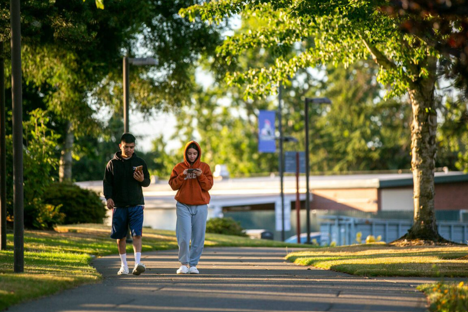 Two students walk along a path through campus Thursday, Aug. 4, 2022, at Everett Community College in Everett, Washington.