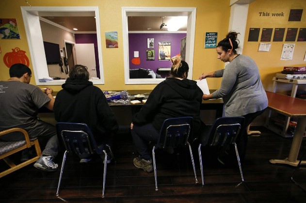 Cocoon House advocate Morgan Huber (right) talks with teens gathered at the nonprofit’s U-Turn drop-in center on Broadway in Everett Dec. 13 2016.