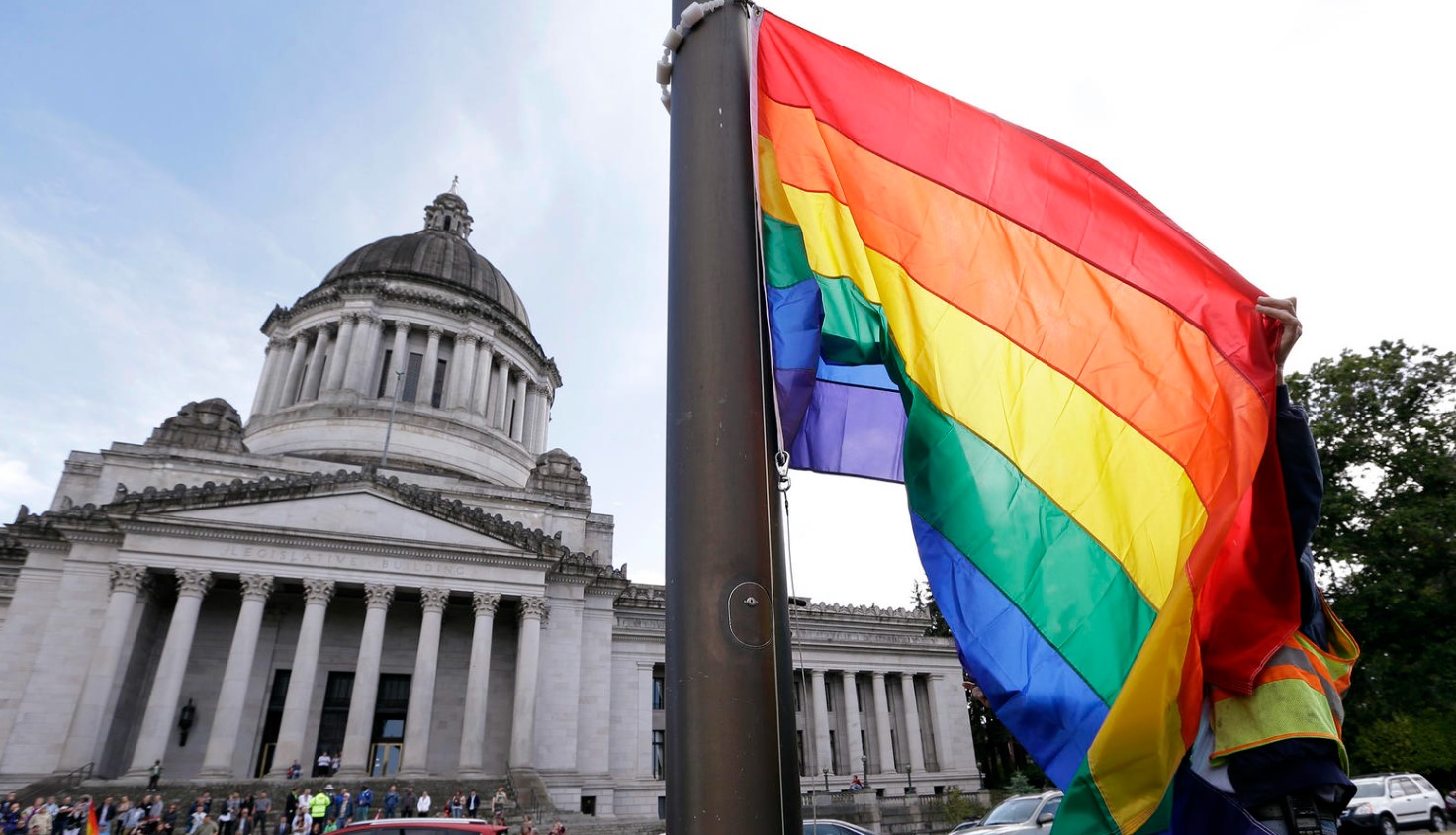 A state worker unfurls a rainbow flag in front of the Washington state Capitol to prepare it to be raised and then lowered to half-staff to observe the mass shooting at the nightclub Pulse in Orlando, Florida, in June 2016.