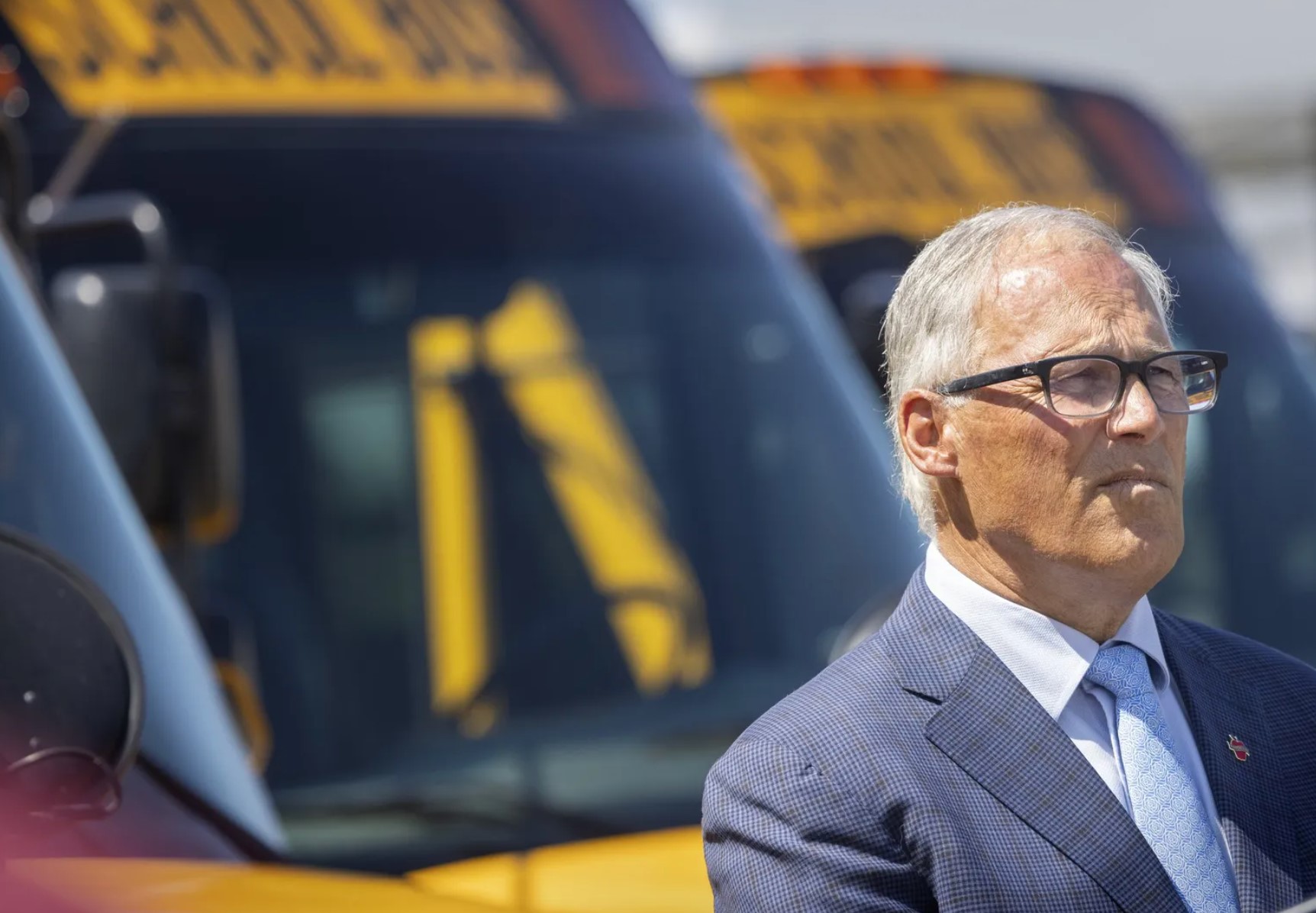 Washington State Governor Jay Inslee stands in front of electric buses during an event at the Highline School District maintenance facility in Burien last summer.