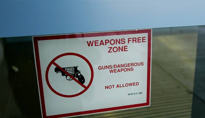 A sign on the main entrance of a Tri-Cities High School references the Revised Code of Washington that makes all schools in the state of Washington off-limits to weapons. Washington lawmakers are now expanding that prohibition to zoos, aquariums, libraries and transit stations. 
