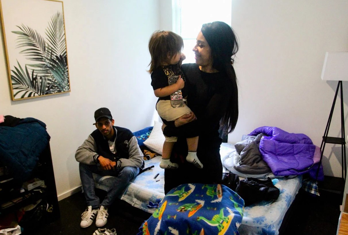 Barbara Peraza-Garcia holds her 2-year-old daughter, Frailys, while her partner Franklin Peraza sits on their bed in their 'micro apartment' in Seattle on Monday, March 11, 2024.