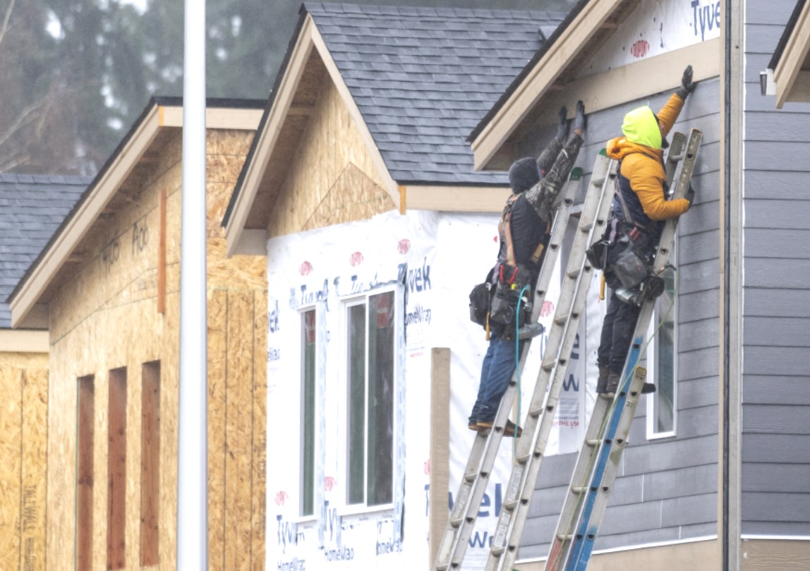 Construction workers hold a piece of siding in place while building houses along Northeast 138th Avenue in east Vancouver. 