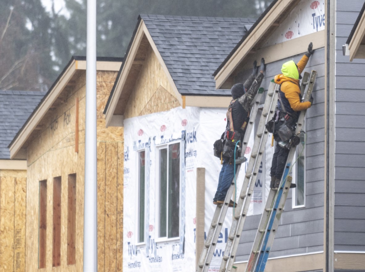 Construction workers hold a piece of siding in place at a development in east Vancouver. The city has awarded millions of local and federal dollars to housing and homelessness services that will produce hundreds of affordable housing units. (Taylor Balkom/The Columbian files)