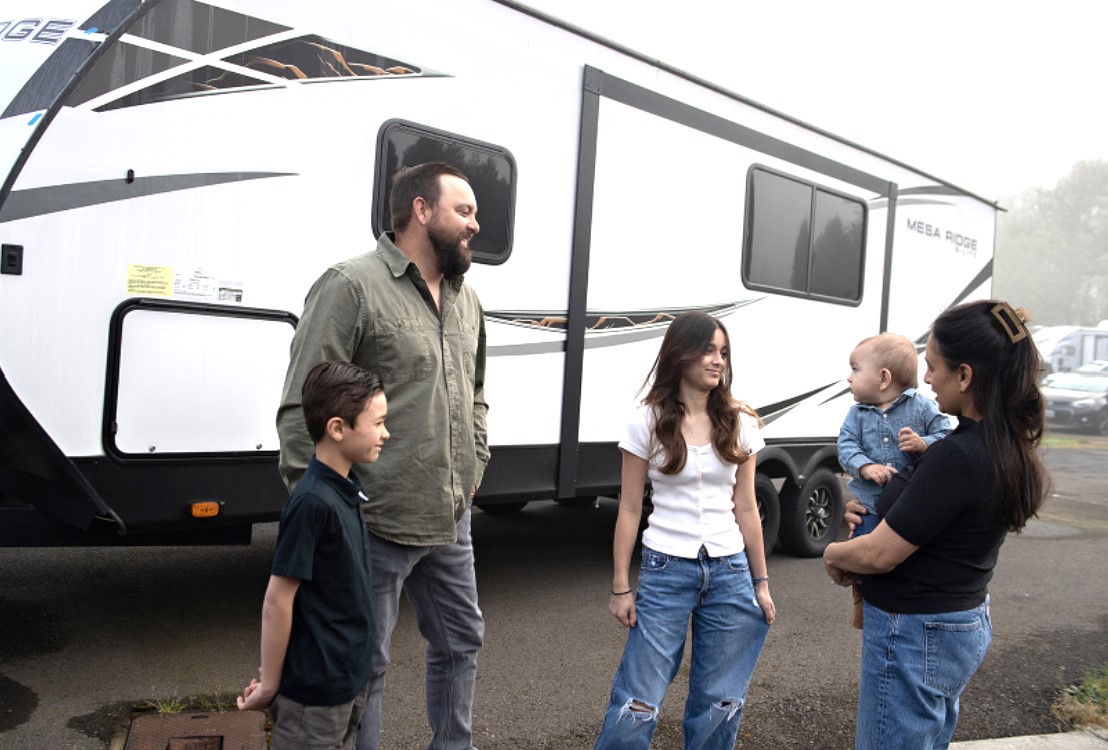 Dylan Bowling, 8, from left, joins father, Chris Bowling, 39, sister, Emma, 13, brother, Wyatt, 10 months, and mother, Crystal Bowling, 38, as they take a break with their recreational vehicle in Ridgefield before dropping it off at the dealership. The family of five moved from a home in California to Clark County for the husband to accept a new job but had trouble finding housing they could afford. (Amanda Cowan/The Columbian)