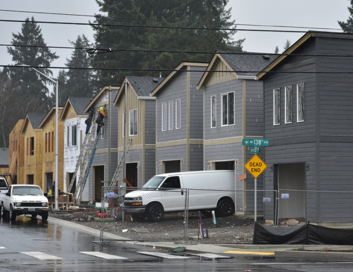 Construction workers hold a piece of siding in place while building houses along Northeast 138th Avenue in east Vancouver. (Taylor Balkom/The Columbian files)