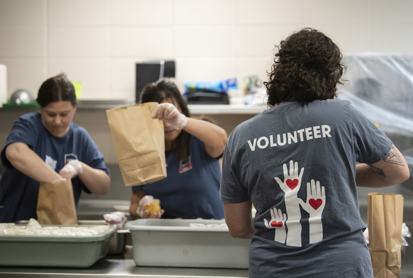 A crew of volunteers at local nonprofit Share Vancouver assemble sack lunches in the kitchen at Fort Vancouver High School in July. State schools superintendent Chris Reykdal announced a new program last week that will provide children across Washington with $120 meal cards to buy groceries throughout the summer. (Amanda Cowan/The Columbian files)
