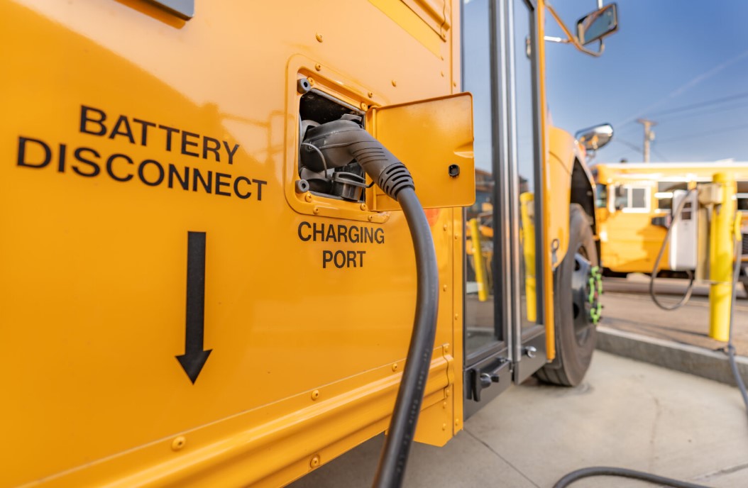 The Biden administration on Wednesday said it will provide funding to help school districts purchase clean school buses, most of them electric. Shown is a yellow electric school bus plugged into a charging station. (Photo by TW Farlow/Getty Images)