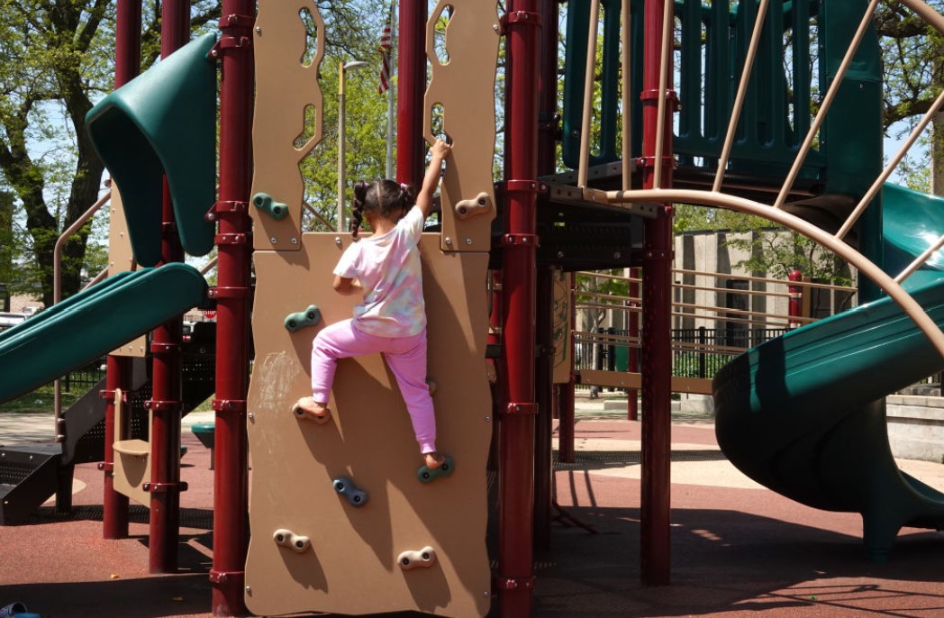  A 5-year-old girl plays on a climbing wall at a playground in Illinois in 2023. Over the past decade, states have worked steadily to recognize the roles of grandparents and other extended loved ones, now known collectively as kinship caregivers, in raising children who otherwise might be in foster care. (Scott Olson/Getty Images)