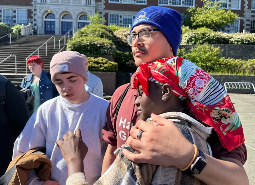 Former Garfield High School student Karima Souleyman is comforted by friends. Souleyman spoke at a community gathering outside school on the morning after a student was fatally shot on campus.