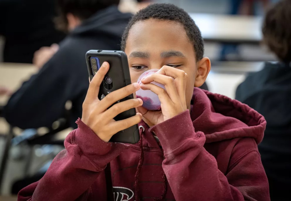 Glover Middle School sixth-grader Michael Parnell, 12, spends some of his lunchtime break looking at his cellphone in June. Next year, the school administration will ban the use of cellphones during the school day. (COLIN MULVANY/THE SPOKESMAN-REVIEW)