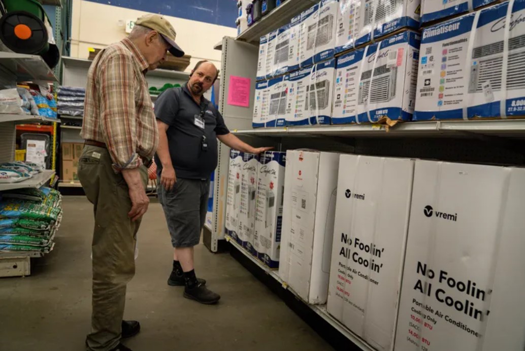 McLendon Hardware store manager Chris Blanchette helps John Woods browse air conditioning units in White Center on Friday. Woods’ air conditioner broke and he was considering buying a new one. (Audrey Richardson / The Seattle Times)