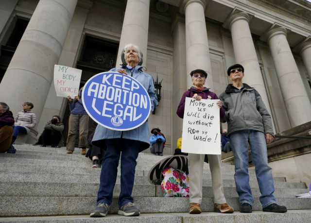 People hold signs in favor of abortion rights as they stand on the steps of the Temple of Justice, which houses the Washington state Supreme Court, during an evening rally, Tuesday, May 3, 2022, at the Capitol in Olympia, Wash. (AP Photo/Ted S. Warren)