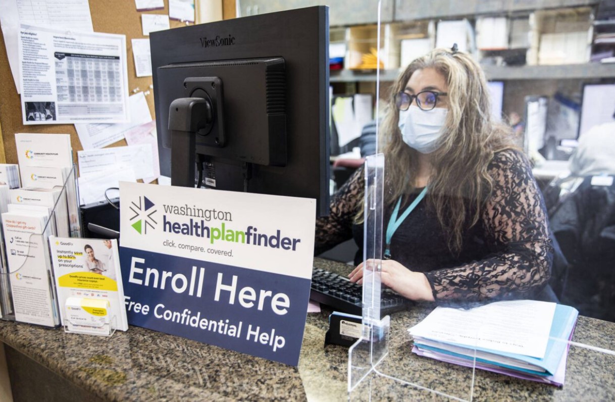 Annaberies Colmena, a patient navigator, sits behind an open enrollment flyer at Sea Mar in 2022 in Everett. (Olivia Vanni / The Herald)