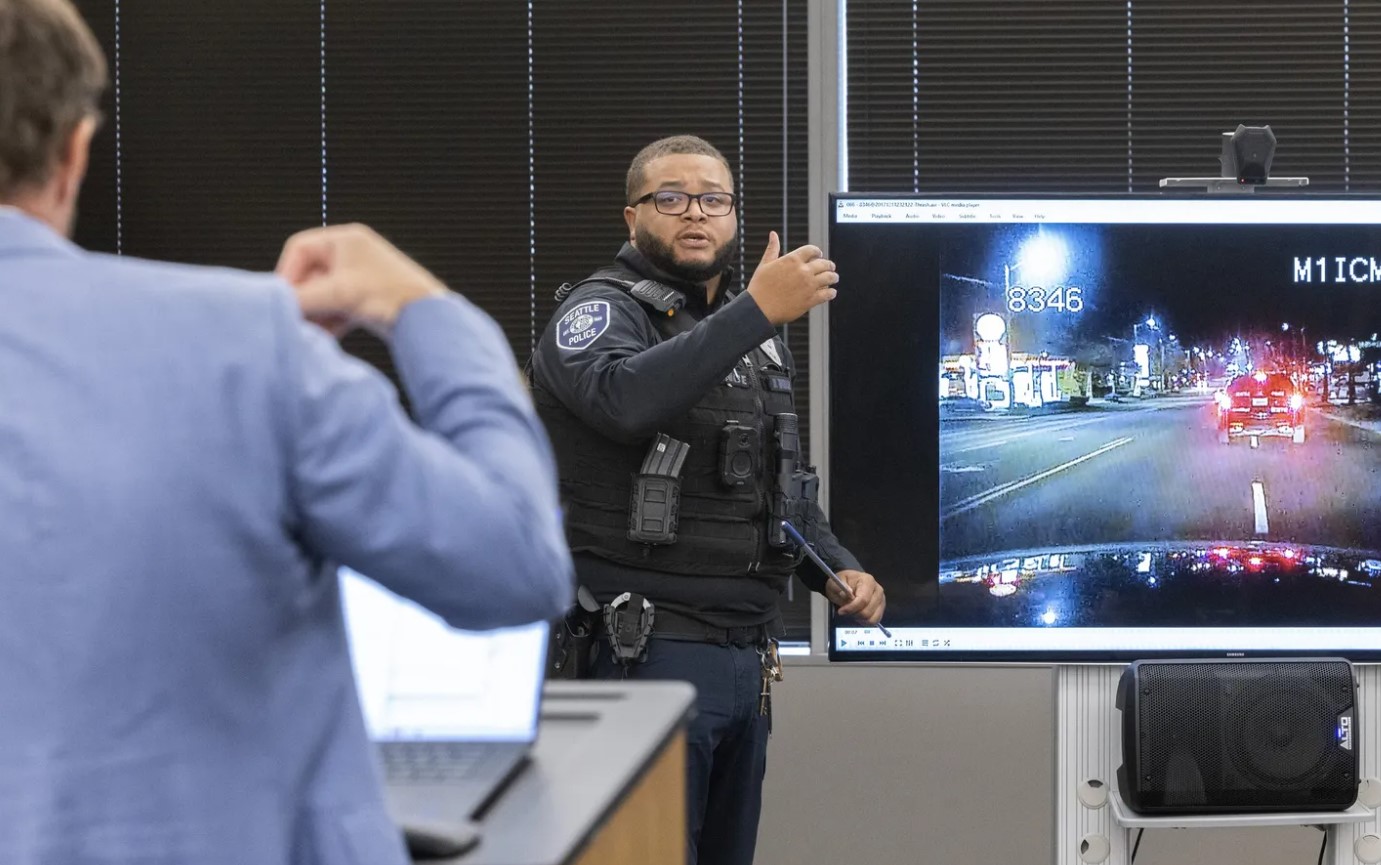 Attorney Matt Anderson, left, questions Seattle police Officer Domisi Thrash during an inquest regarding the death of Kyle Gray on Wednesday in the Chinook Building in Seattle. Gray was killed in December of 2017 and the inquest is finally taking place. On the screen is dashboard footage from Officer Thrash’s car... (Ellen M. Banner / The Seattle Times)