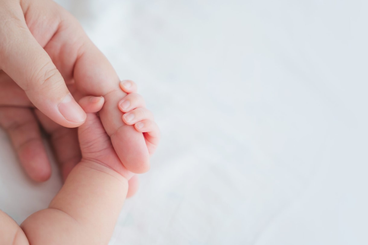 A photo of an adult holding a baby’s hand.