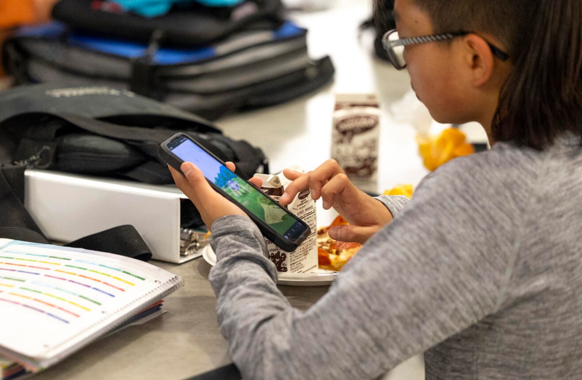 A student uses a smart phone during their lunch break at Goodman Middle School in Gig Harbor, which allows phones at lunch but otherwise has a district-wide ban, on Monday, Sept. 9, 2024. (Jason Redmond for Cascade PBS)