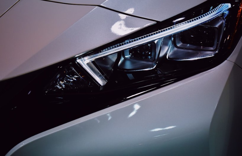 Close up of a car headlight on a white electric sedan