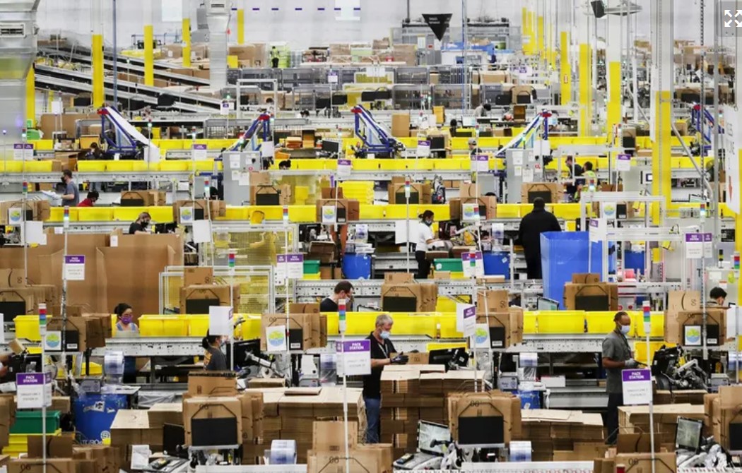 Workers work at packing stations at Amazon’s Kent fulfillment center. Two Amazon employees in the retail and warehouse division said in a new lawsuit filed this month Amazon restricted their options for work after... (Ken Lambert / The Seattle Times, 2020)