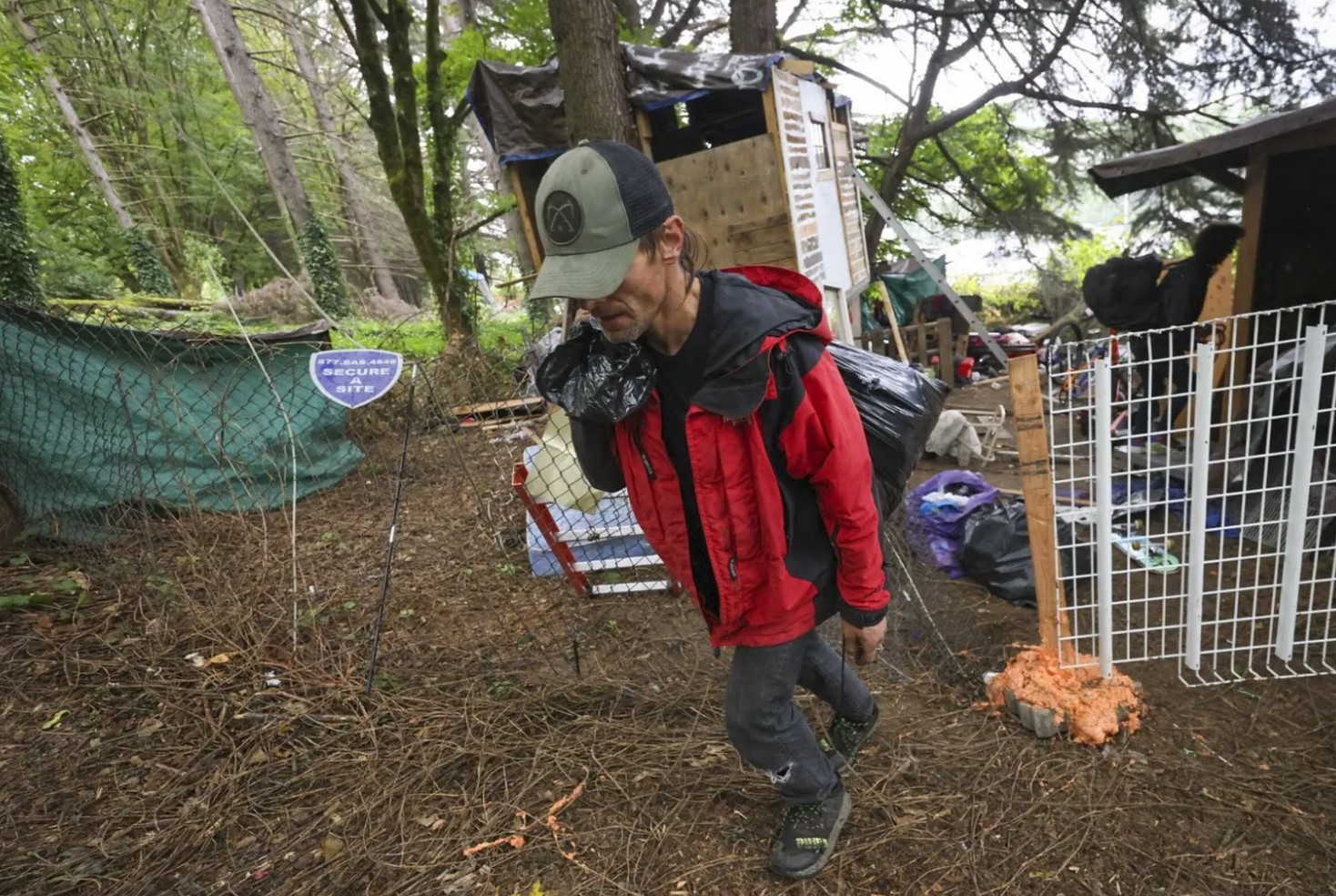 Garrett Hahn, 45, carries a bag of belongings away from where he lived at an encampment site under removal order in Seattle, on Wednesday, September 25, 2024. (Ivy Ceballo / The Seattle Times)