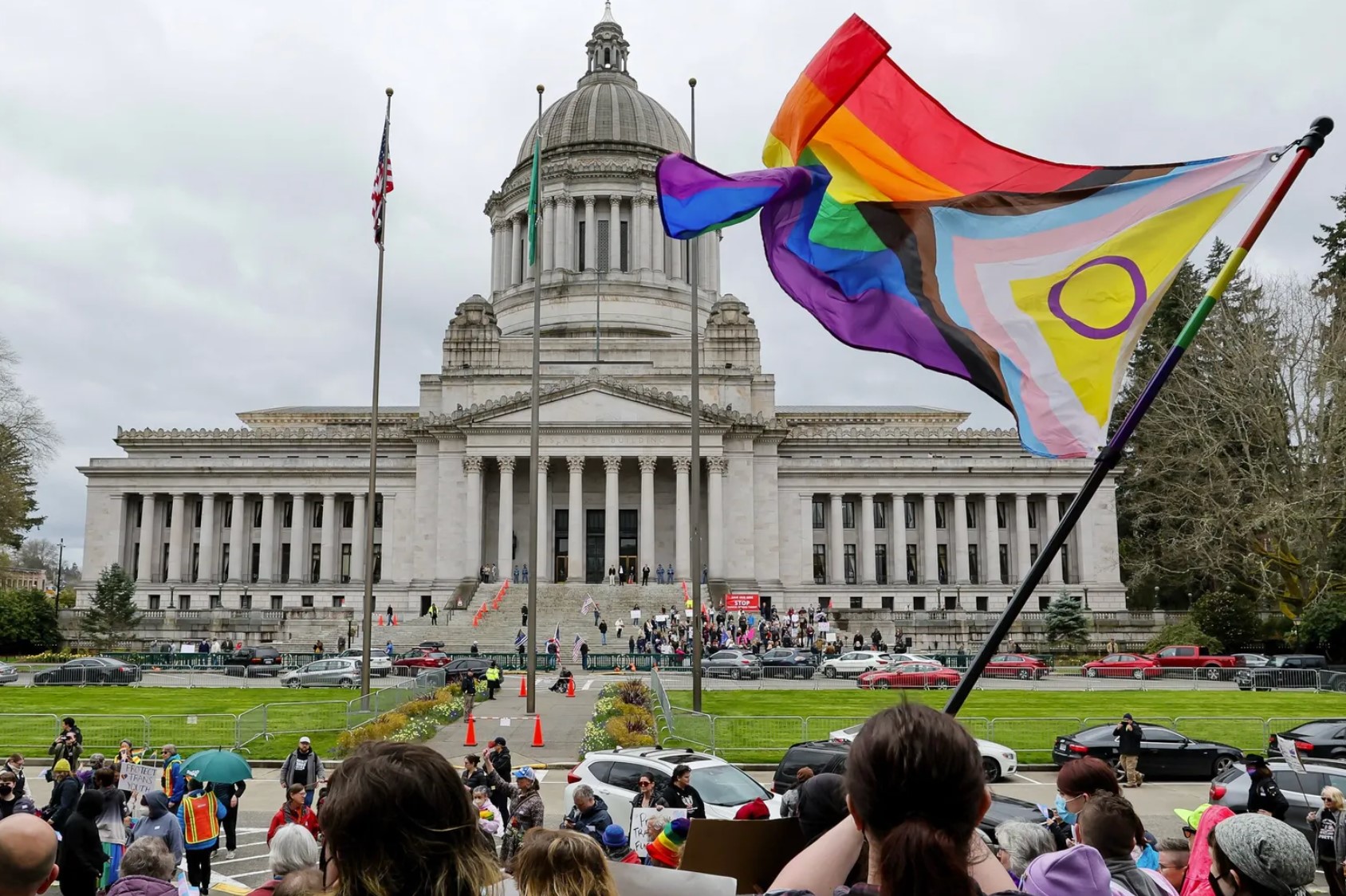 A supporter of trans rights waves a flag in front of the Temple of Justice in Olympia as an opposing rally gathers on the steps of the Washington state Capitol to protest legislation to exempt youth shelters from... (Jennifer Buchanan / The Seattle Times, 2023)