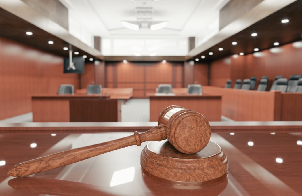 Close up of a gavel sitting atop a dias in a courtroom.