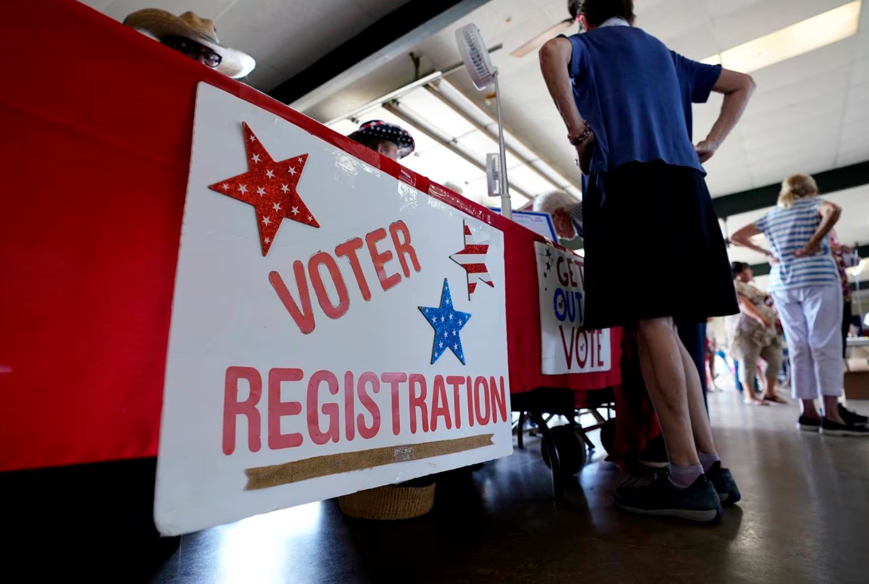 Person standing in front of a table with a sign that says voter registratoin