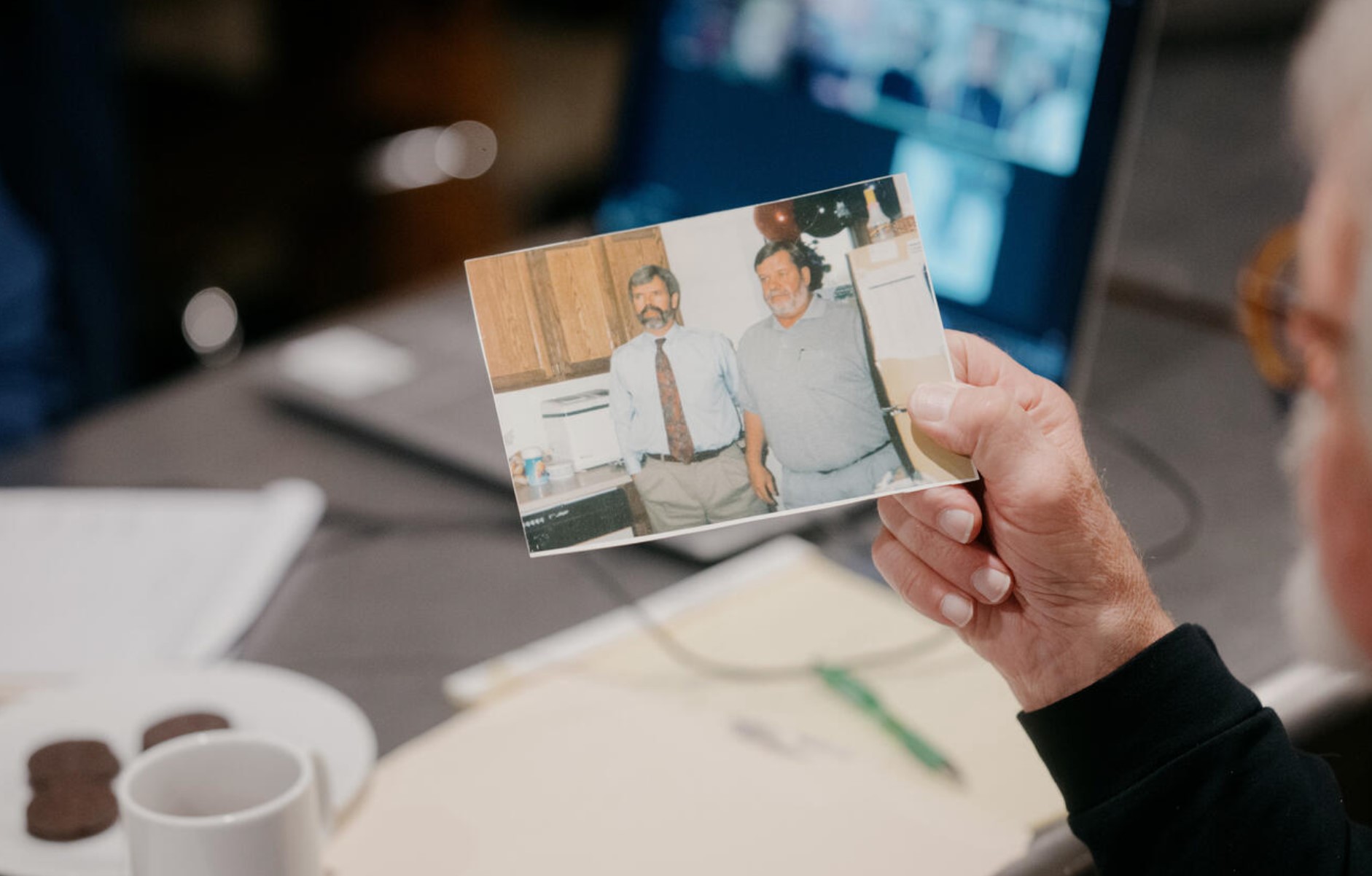 Patrick Johnson, President of the Jefferson County National Alliance on Mental Illness, shows a portrait taken with his twin brother Mike Johnson (right), who took his own life 25 years ago, to other support group members at Recovery Cafe in Port Townsend on November 6, 2024. (Grant Hindsley for Cascade PBS)