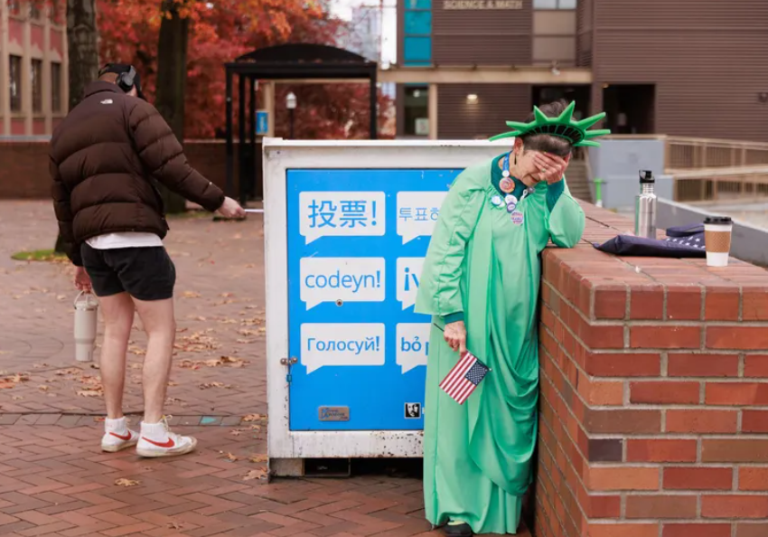 Patti Gorman, also known as “Ms. Liberty,” puts her head in her hands while having conversations at the ballot drop box outside Seattle Central College in Seattle, Nov. 5, 2024. Gorman, a service-learning coordinator at the college, says she has been dressing as “Ms. Liberty” for years to engage community members in the voting process and give out stickers