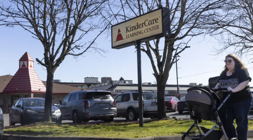 Nicole Slemp, a new mother of 7-month-old William, pushes her son in his stroller past KinderCare, which is near the family’s Auburn home on March 14, 2024. Sleep recently quit her job because she and her husband couldn’t find child care they could afford. Expensive, scarce child care is putting Puget Sound parents out of work. (Ellen M. Banner / The Seattle Times