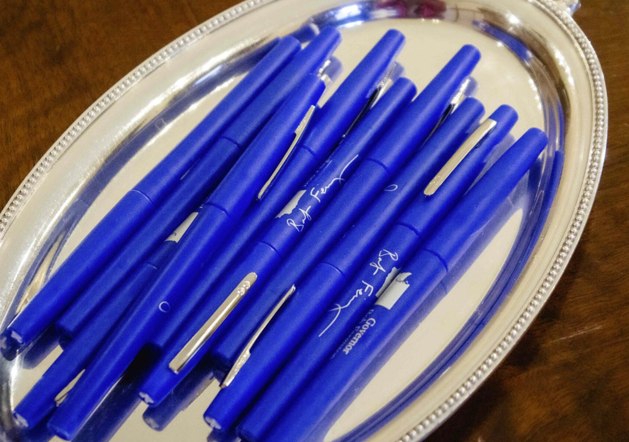 Seen here are the blue pens Gov. Bob Ferguson uses to sign bills. Companies and other interest groups are hoping he'll opt for red veto ink on a range of tax bills. (Photo by Jacquelyn Jimenez Romero/Washington State Standard)