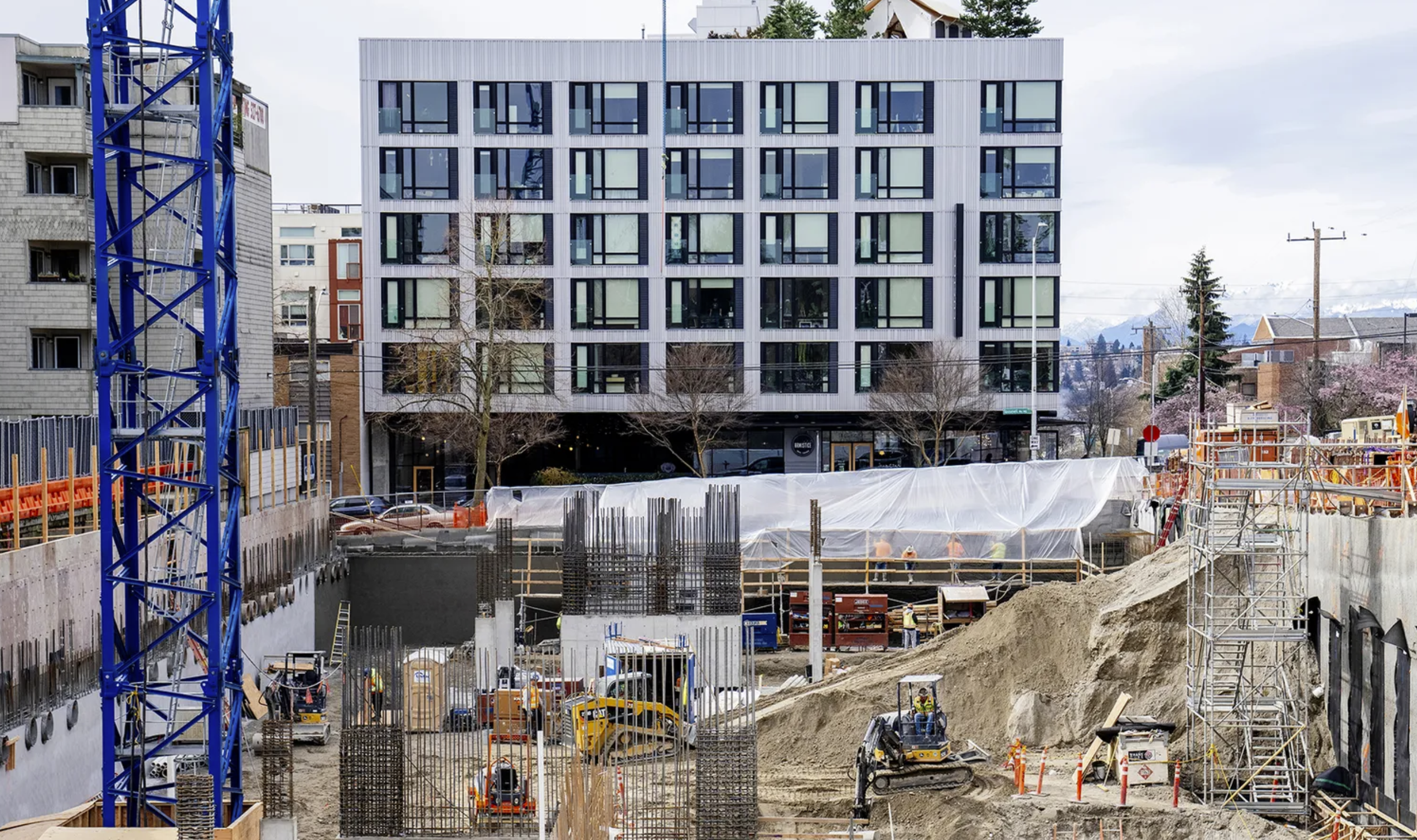 Construction crews work on a building in the Roosevelt Urban Village area near Roosevelt High School on Friday, March 14, 2025. New apartment buildings will be exempt from rent cap laws recently passed. (M. Scott Brauer/Cascade PBS)