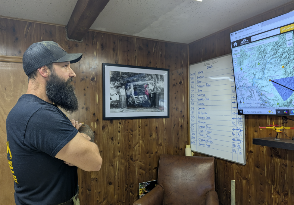 Kane Steinbruecker, chief fire warden of the Clearwater-Potlatch Timber Protective Association, checks a monitor with maps and different camera angles of the forests. (Credit: Lauren Paterson / NWPB)