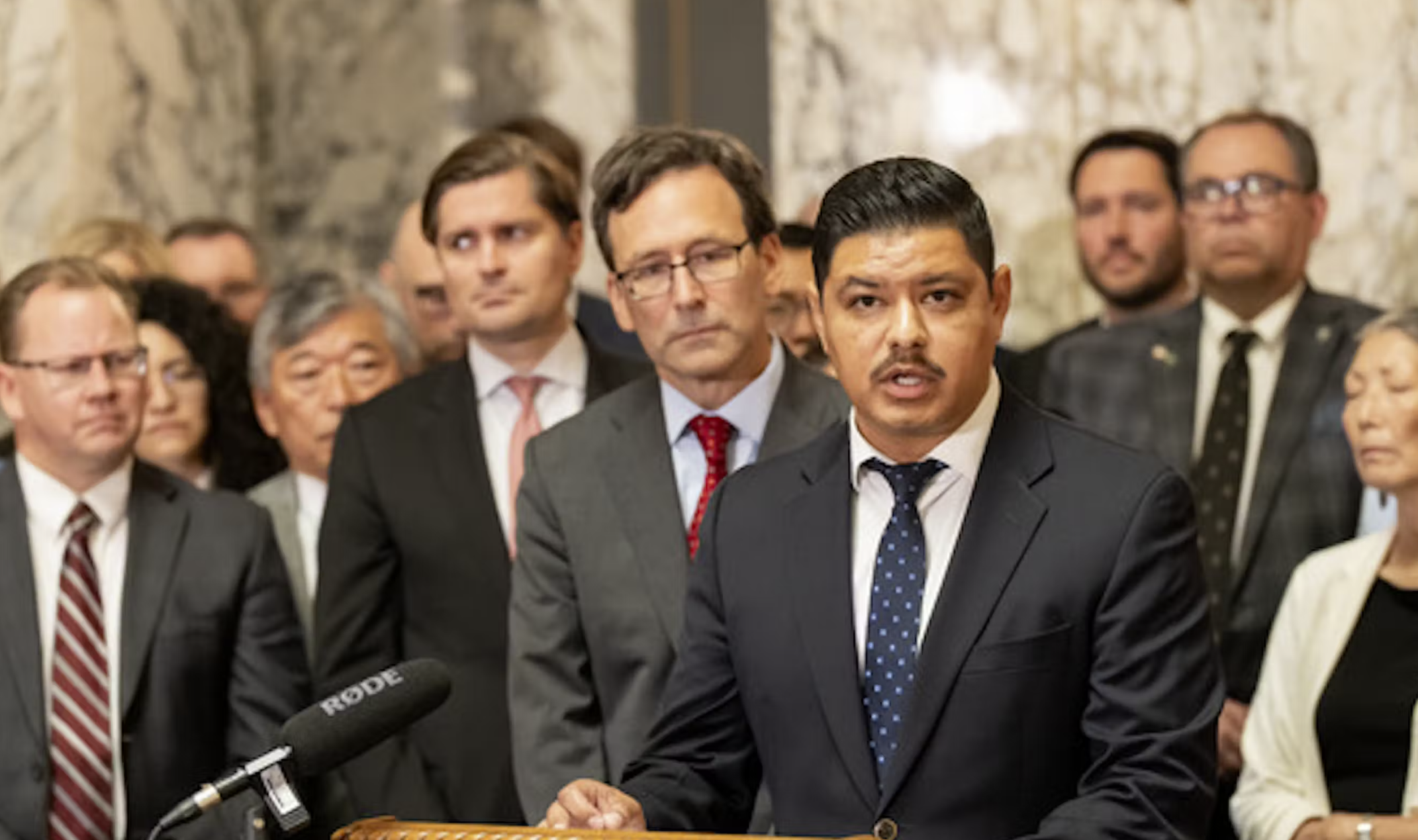 Everett Representative Julio Cortes, a Democrat, speaks to press in Olympia Tuesday, Aug. 19, in response to a letter from U.S. Attorney General Pam Bondi. Behind Cortes, from right to left, are Gov. Bob Ferguson, state Treasurer Mike Pellicciotti, Seattle state Senator Bob Hasegawa, and state Superintendent of Public Instruction Chris Reykdal.