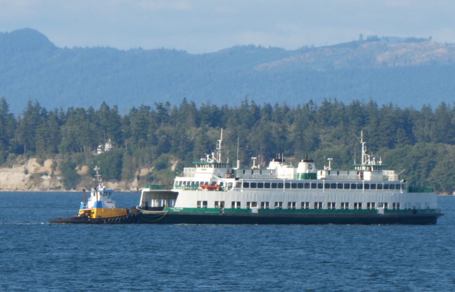 Washington State Ferries will need to keep its oldest ferries running for at least five more years before relief arrives. Shown here is the 66-year-old Tillikum being pushed by a tug after a summer breakdown. (Photo by Tom Banse)