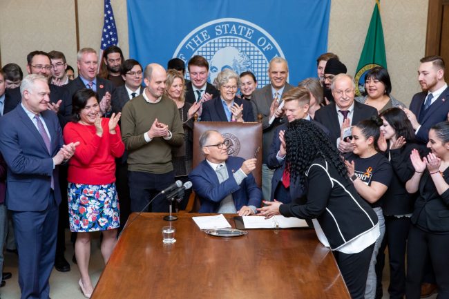 Bill signing in the governor's office for SB 6492 - legislators and advocates surround governor and applaud 